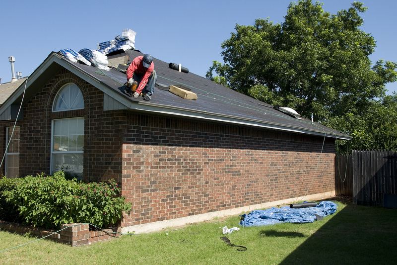 Roofer working on the roof of a brick house